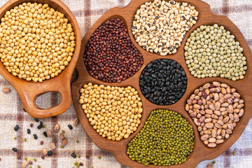 Variety of colorful beans in wooden containers, top view, healthy eating concept
