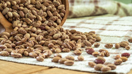 Organic borlotti beans poured from wooden bowl on the table, healthy food