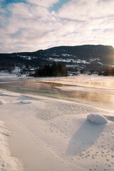 The river is about to freeze. It is very cold and the river is much warmer than the air, therefore the smoke or the damp from the river. Shot at Gol, Norway in February. Minus 20 degreases Celsius. 