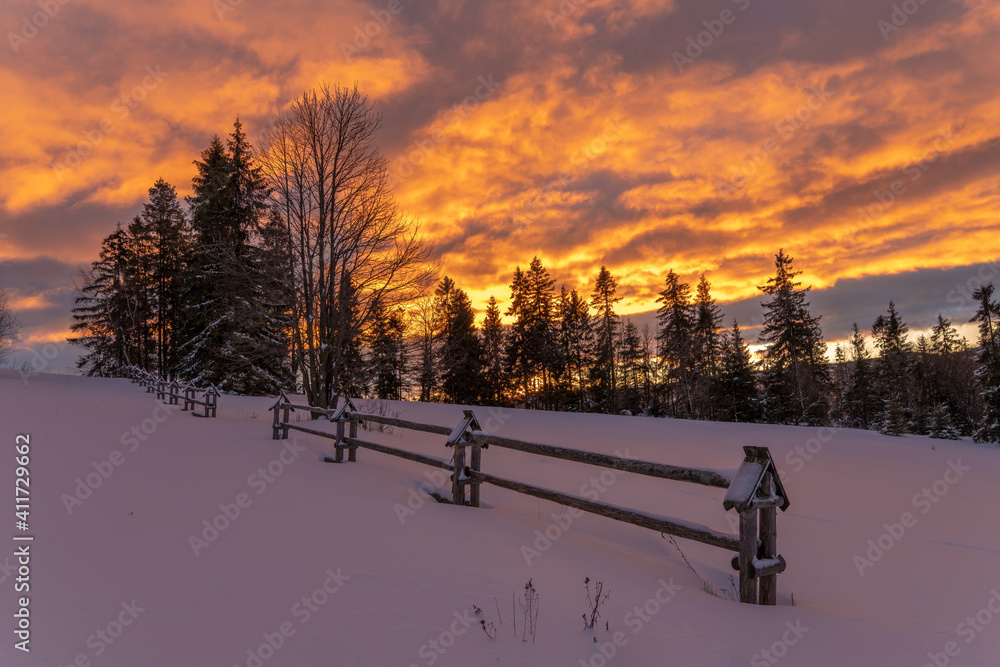 Wall mural a fiery, dramatic sunrise in a winter mountain scenery
