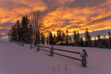 A fiery, dramatic sunrise in a winter mountain scenery