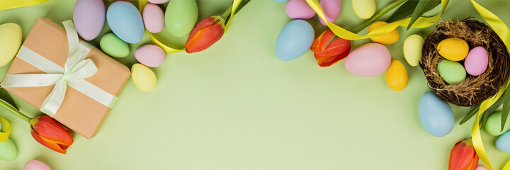 Stylish background with colorful easter eggs pastel colors isolated on green background. Horizontal long banner for web design. Flat lay, top view, mockup, overhead, template