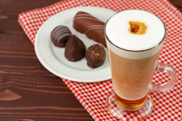Cup of coffee and saucer with chocolate sweets on wooden table