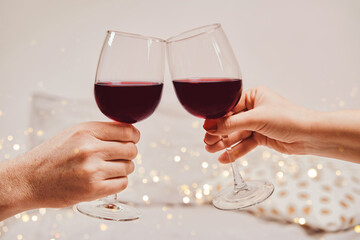 Hands of a man and a woman are holding glasses of wine. Romantic atmosphere, soft focus, bokeh, close-up