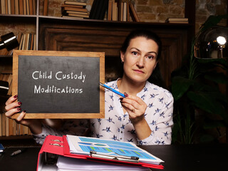 Hand holding a chalkboardwith inscription Child Custody Modifications . Close up white chalkboard.
