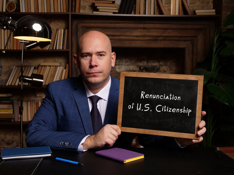 Business Man Holding Chalkboard With Written Text Renunciation Of U.S. Citizenship - Closeup Shot.