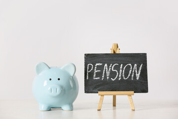 Piggy bank with savings and chalkboard with word PENSION on light background