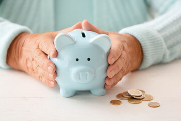 Senior woman with piggy bank at table. Concept of pension - obrazy, fototapety, plakaty