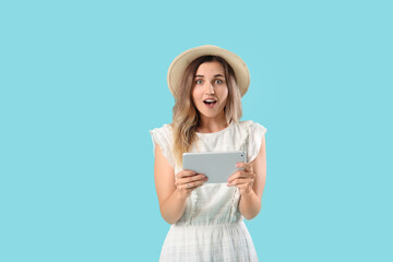 Surprised young woman with tablet computer on color background