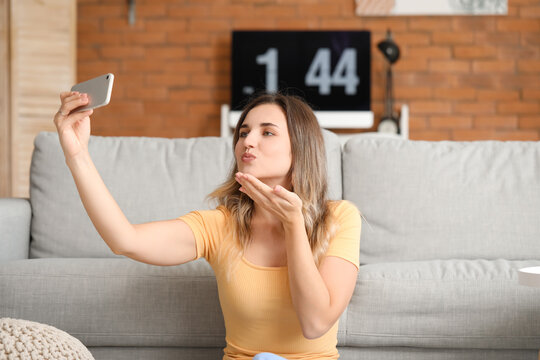 Young woman with mobile phone video chatting at home