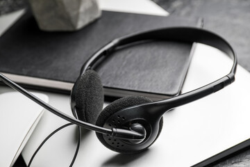 Headset with notebook and laptop on table, closeup