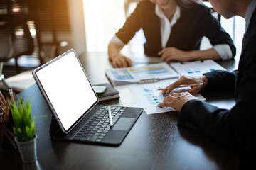 Young Asian businessman Sitting and working at a desk With market analysis sheet, Tablet, PC