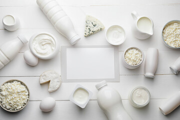Different dairy products without lactose and blank card on light wooden background