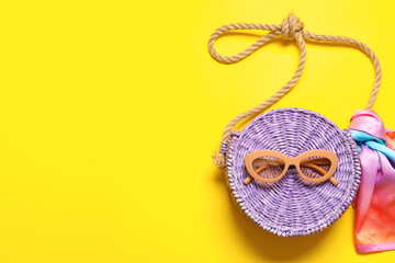 Stylish sunglasses and bag on color background