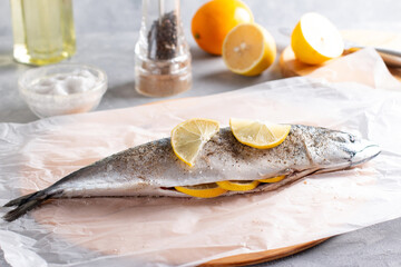 Mackerel fishes ready for cooking decorated with lemon slices, spices on the table