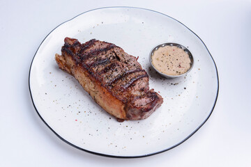 Delicious beef steak with sauce served on a white plate over white background. BBQ meat, barbecue...