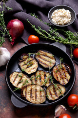 Frying pan with tasty grilled eggplant on color background