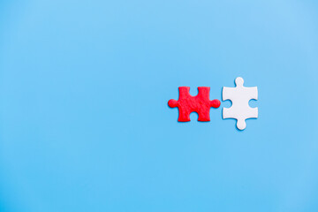 Obraz premium White and red jigsaw puzzle on a blue background. Copy space for text, top view, close up.