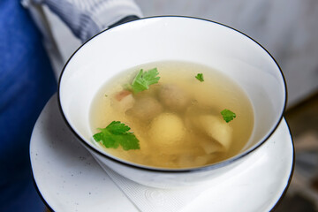 Bowl of Chinese noodle soup with chicken broth and mushrooms. Served by waiter in restaurant or diner.