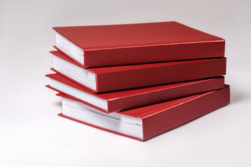 Stack of red hardcover books or reports on white background. Copy space.