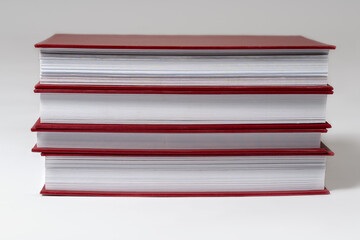 Stack of red hardcover books or reports on white background. Copy space.