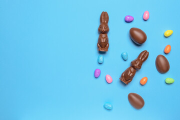 Tasty chocolate Easter bunnies and eggs on color background