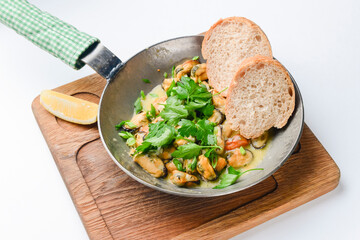 Delicious fresh steamer clams with garlic and basil served in a pan with toast bread over white background.