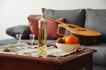 Fototapeta na wymiar Bottle of brandy and bowl with fruits on the table in living room