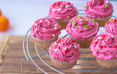 muffins with scarlet cream and decor , pearls and red and green stars. holiday cupcakes on a metal stand on a wooden background. High quality photo