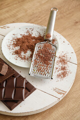 Tray with plate, chocolate and grater on table in kitchen