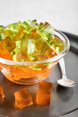 Glass bowl with tasty jelly cubes on table, closeup