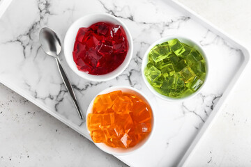 Bowls with tasty jelly cubes on tray