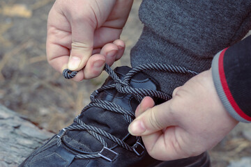 Women's Hands are tying their shoelaces outside.