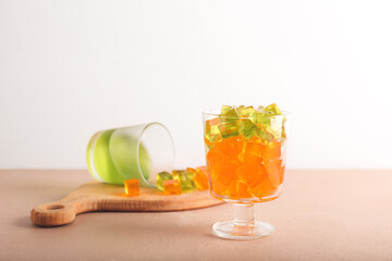 Glass with tasty jelly cubes on table
