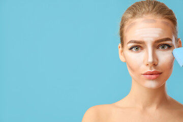 Beautiful young woman applying contouring makeup against color background