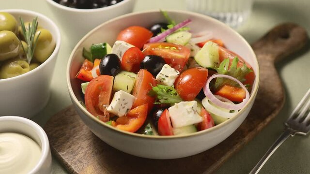 Greek salad with fresh vegetables, feta cheese, olives, herbs. Close-up, the camera moves along 