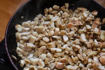 Raw mushrooms are fried in a pan.
