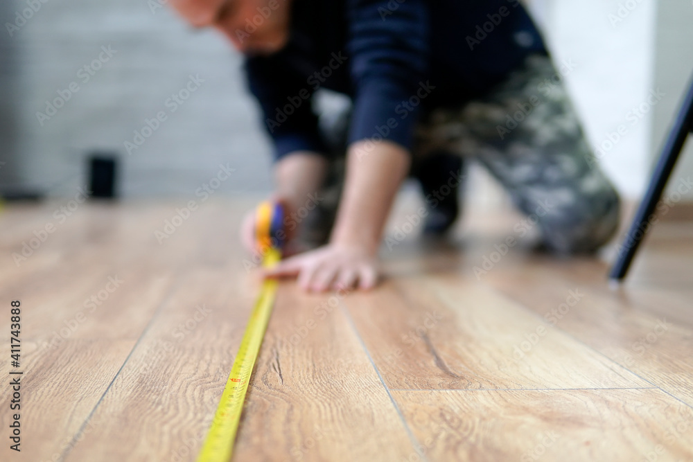 Wall mural worker guy measures the length of the room. Focus on the ruler. The man is out of focus.