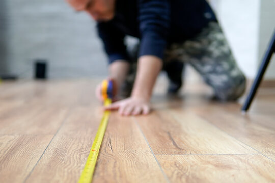worker guy measures the length of the room. Focus on the ruler. The man is out of focus.