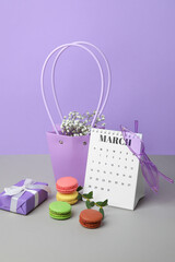 Calendar with flowers, macarons and gift on color background. International Women's Day celebration