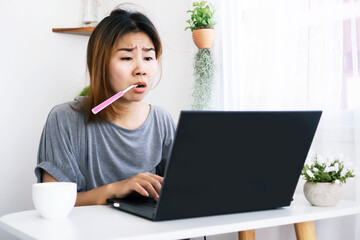 workaholic Asian woman busy with working hard from home office and brushing teeth at desk