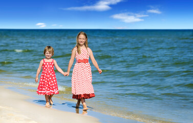 Two cute little girls walking on the beach