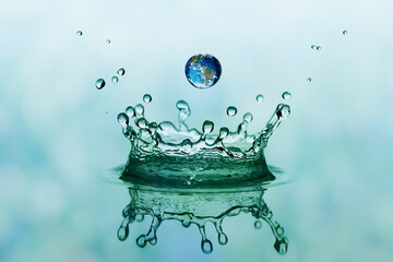 Green water splash in crown shape and falling drop with earth im
