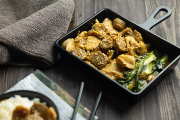 Tumis Ayam Bakso or chicken and meatball sauteed with barbeque sauce, pock coy, and sesame seed. Dark wooden background. 
