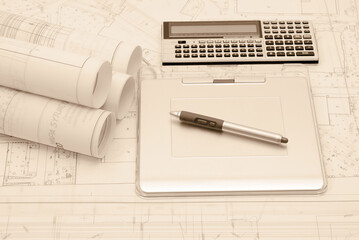 Rolled-up architectural plans with tablet and calculator