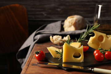 Maasdam cheese and fresh bread, a glass of white wine, a sprig of rosemary for a delicate aroma, cherry tomatoes, delicious and healthy food.