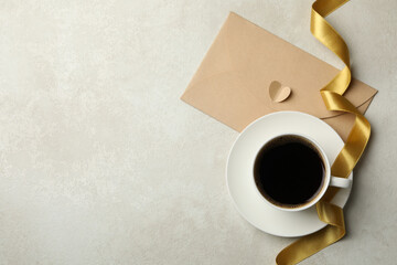 Cup of coffee, ribbon and envelope on textured background