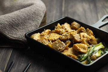 Tumis Ayam Bakso or chicken and meatball sauteed with barbeque sauce, pock coy, and sesame seed. Dark wooden background. 
