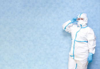 Fototapeta na wymiar Medical worker in a white protective suit on a blue background. Wear a respirator and gloves. Place for an inscription. Panorama.