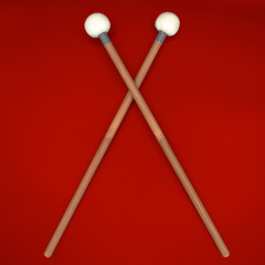 Crossed timpani mallets on a grey background.
